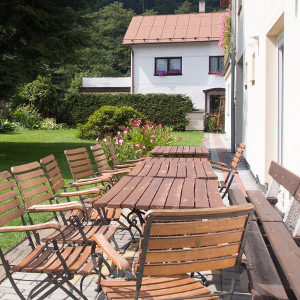 Stühle und Tische und Gril im Gargen vor der Pension